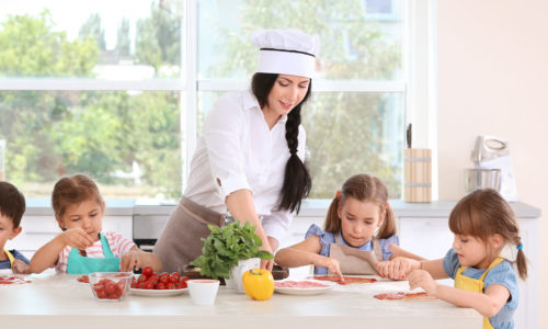 Group of children and teacher in kitchen during cooking classes