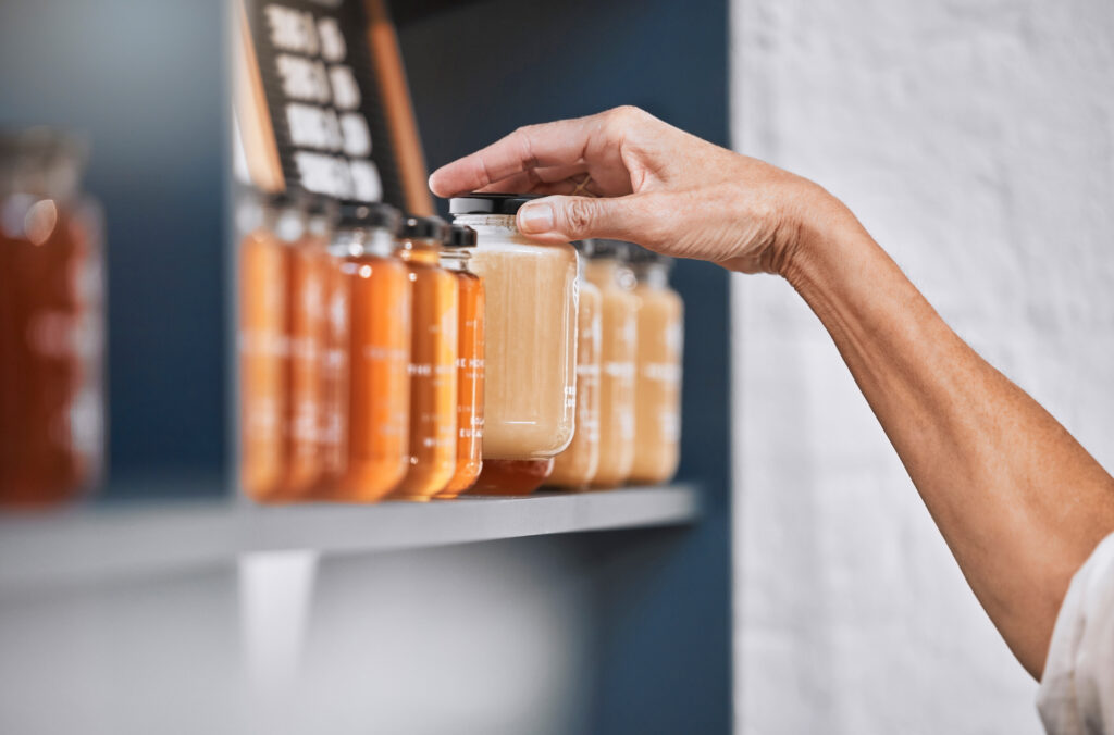 Honey, product and retail with hands of woman for natural, supermarket and grocery shopping shelf. Food, health and sustainability with organic store employee for small business, sale and choice.